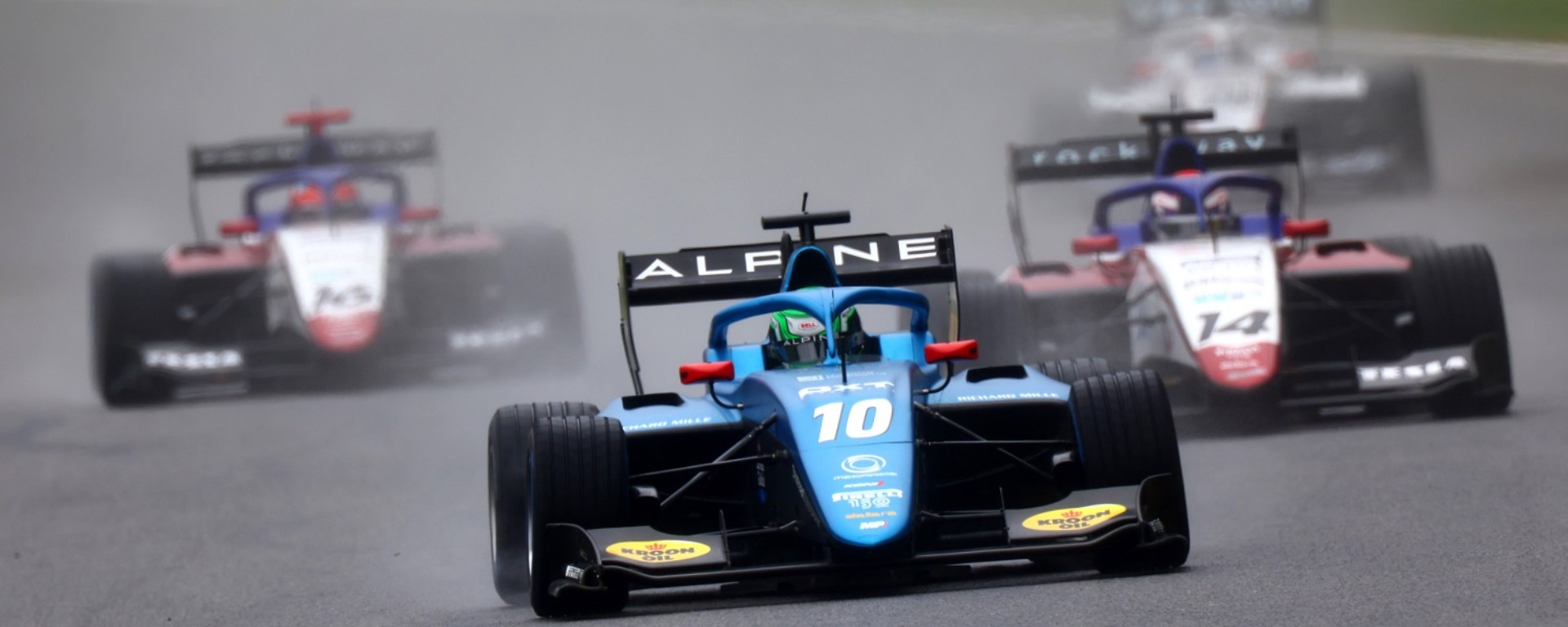 Blue car facing the camera with 3 cars behind it and rain and mist in the air.