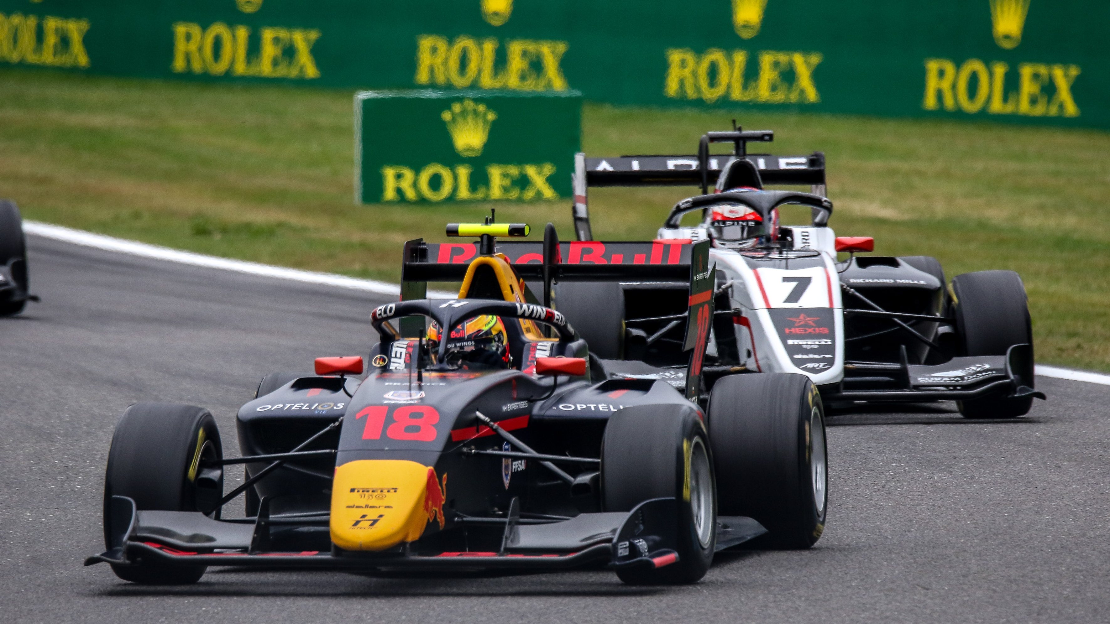 Black and red formula car facing the camera to the left slightly with black and white formula car behind it facing the camera to the right.