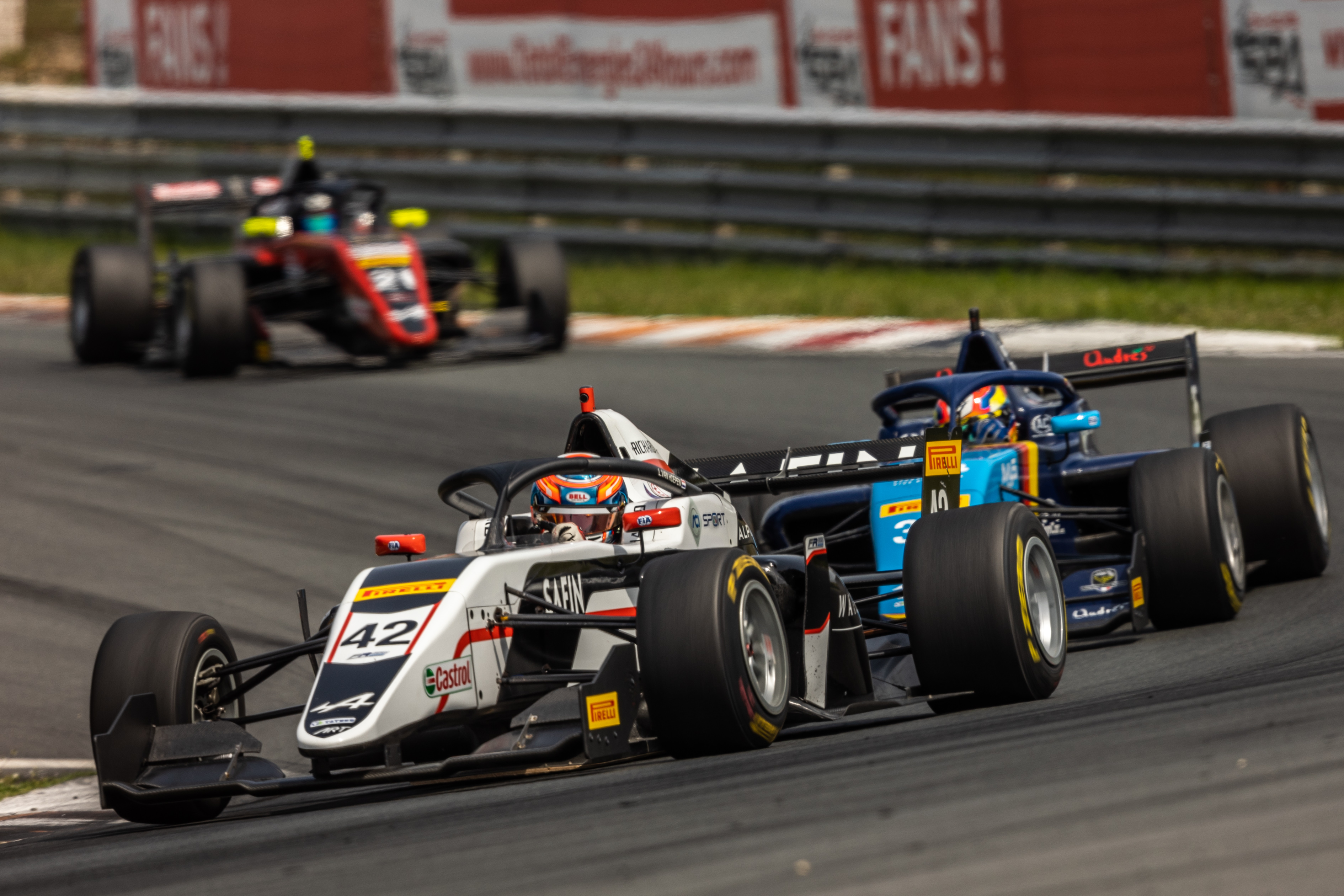 The black-and white car of FRECA driver Laurens van Hoepen leads the blue and navy FA Racing car of Nicolás Baptiste through the right-hand Turn 2 at Race 1 on the Circuit Zandvoort.
