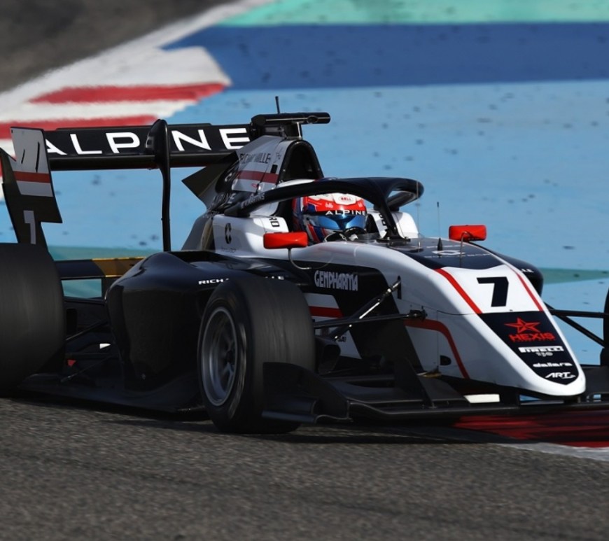 Black, white, and red formula car drives to the right of the camera.