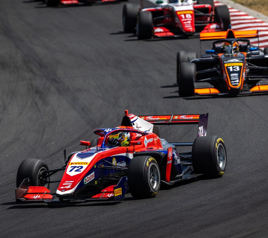 The red, white, and blue #72 FRECA single-seater car driven by Leonardo Fornaroli makes a right turn, pursued by the orange and black car of Joshua Dufek #13.