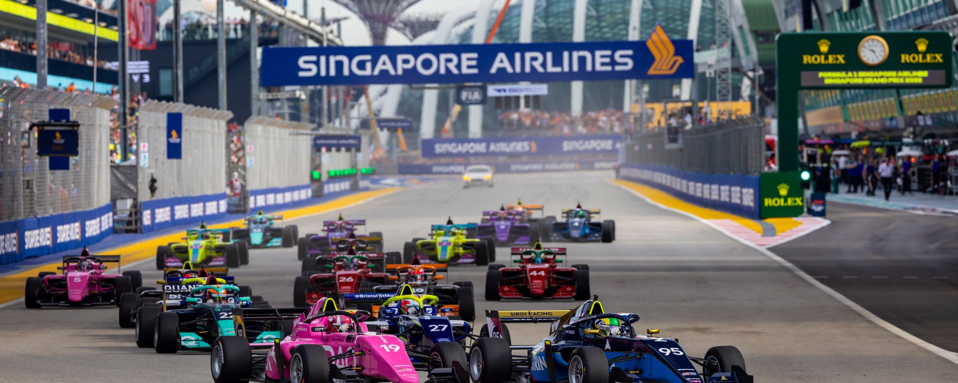 A grid of 18 cars prepares to make the left turn into Turn 1 at Singapore's Marina Bay Circuit on an overcast afternoon