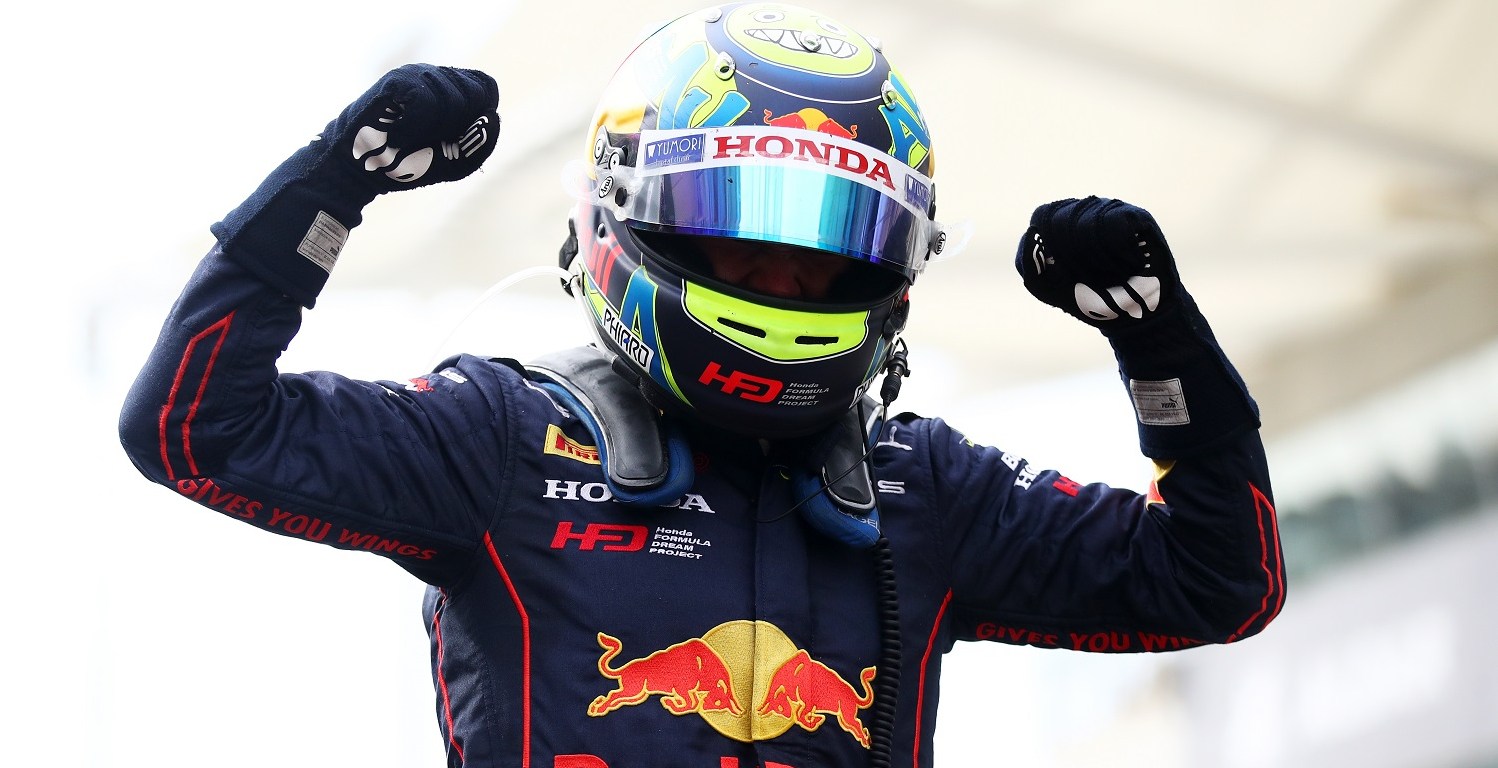 Ayumu Iwasa, wearing his neon yellow and blue helmet and his blue Red Bull–branded racing suit, lifts both fists in celebration