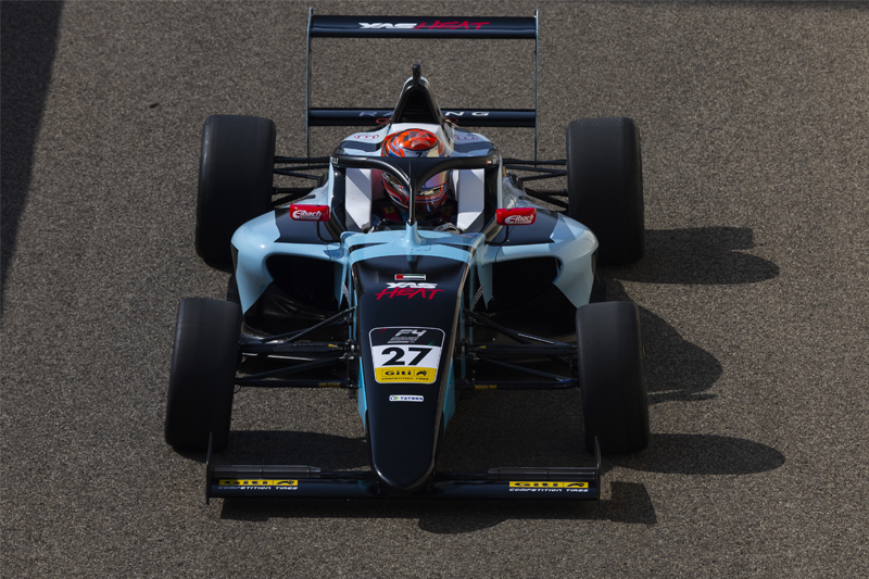 A blue, black and red car driven by a driver with a red crash helmet