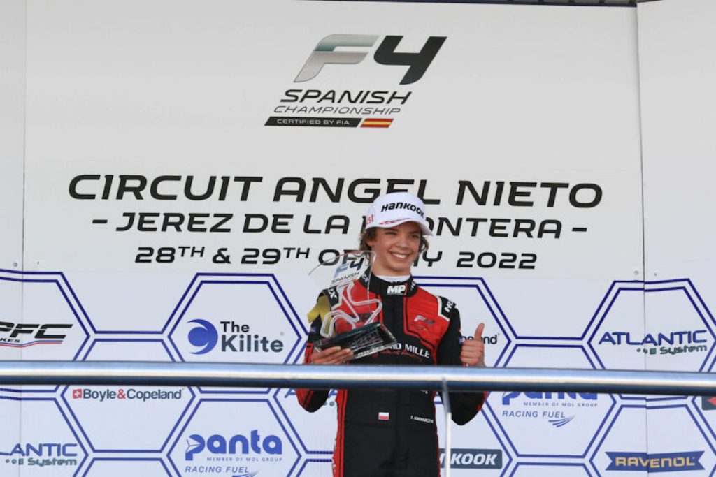 Tymoteusz Kucharczyk holds a trophy in his right hand and gives a thumbs up to the camera. Behind him, the podium text reads "Circuit Angel Nieto – Jerez de la Frontera – 28th & 29th of May 2022