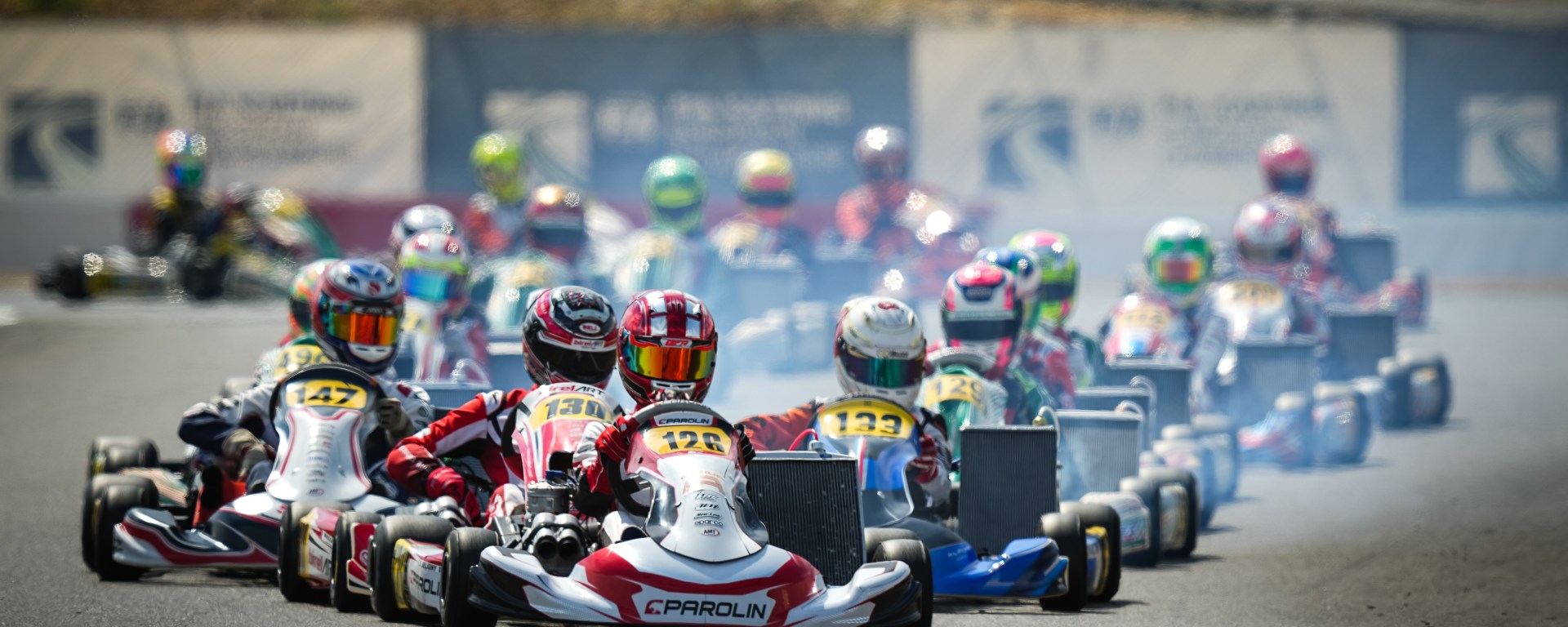 Karts lined up two by two on a racetrack, led by a red and white kart (driven by Enzo Deligny)