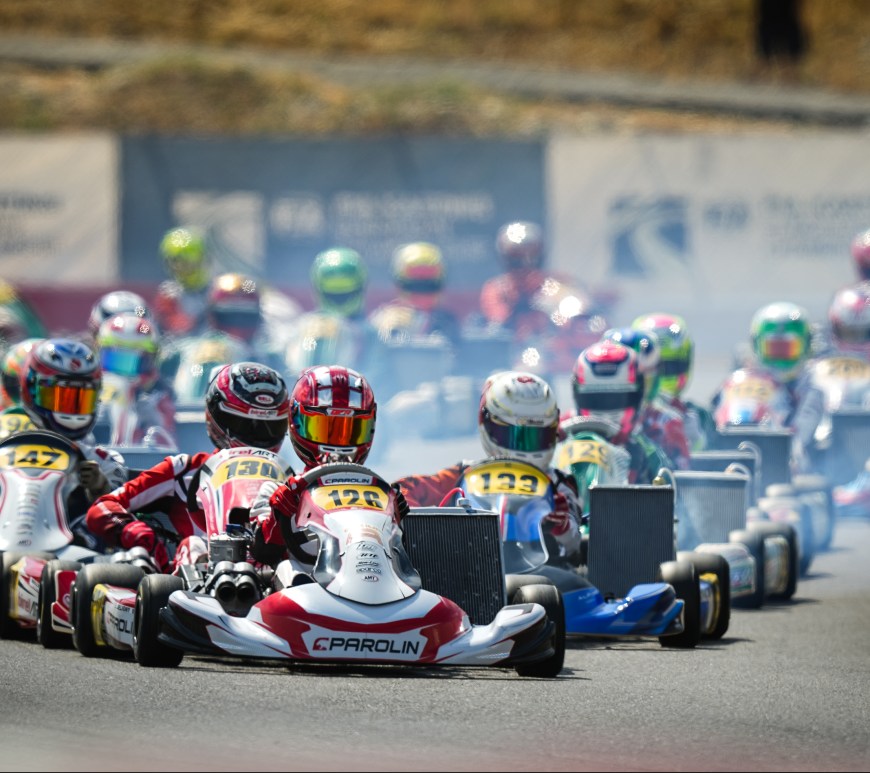 Karts lined up two by two on a racetrack, led by a red and white kart (driven by Enzo Deligny)