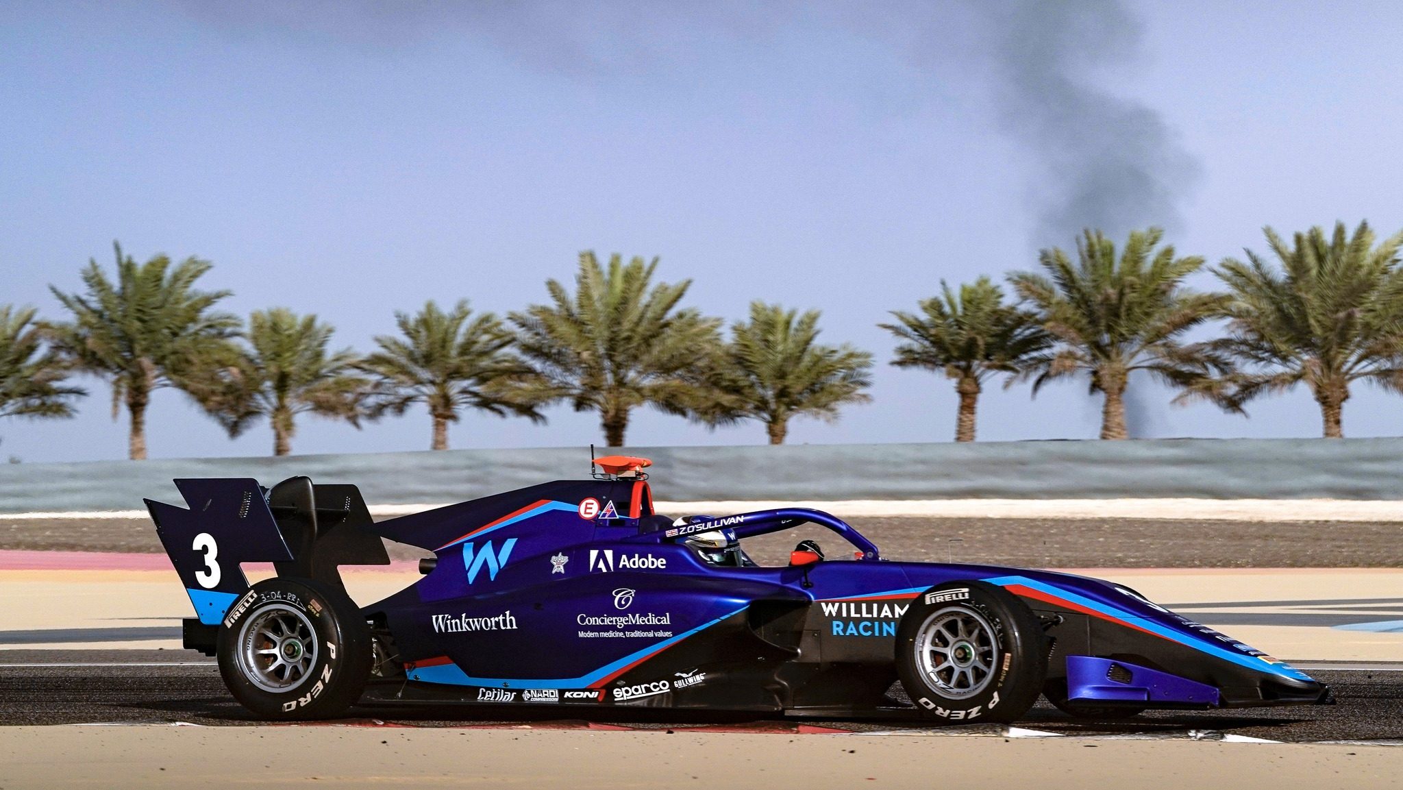 Blue FIA F3 car with Williams logo driving on track in front of palm trees