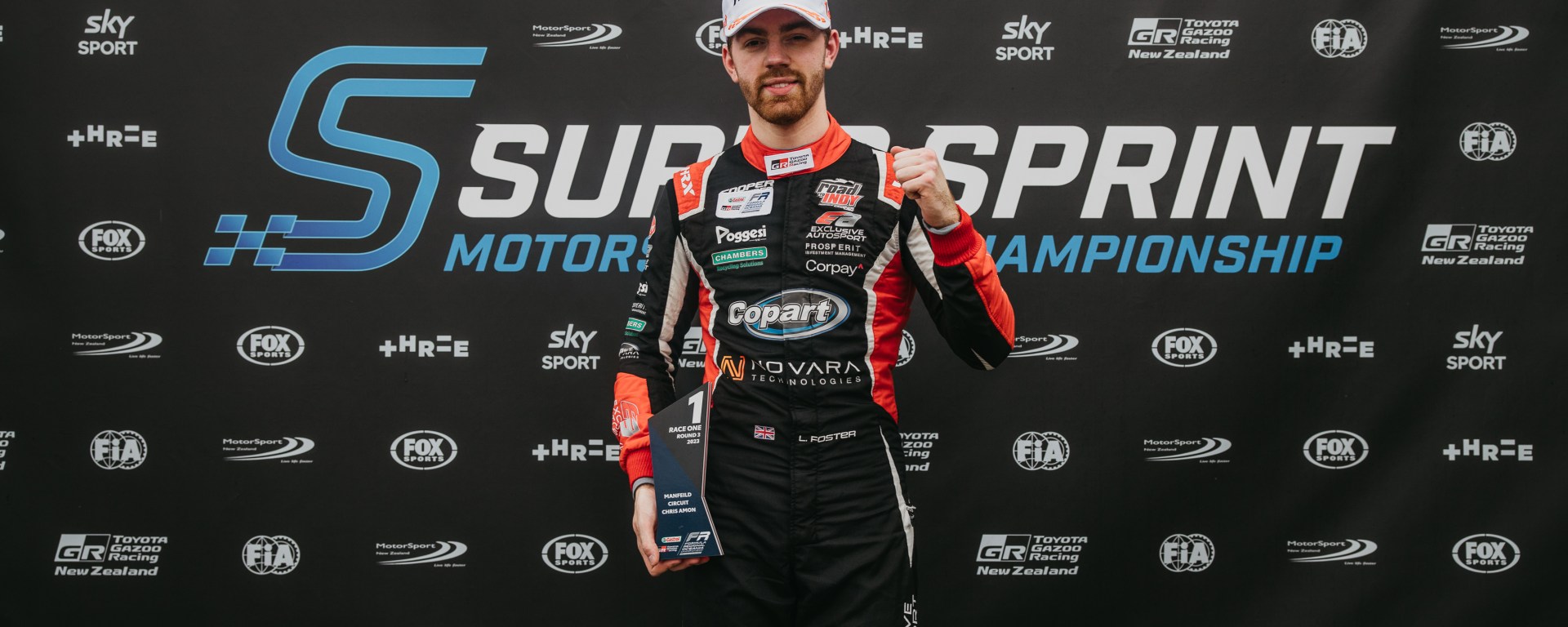 Louis Foster pumps his left fist while holding a first-place trophy in his right hand