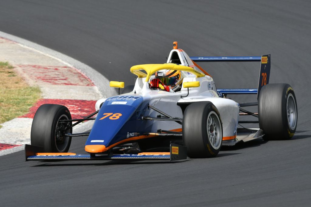 A blue and white Italian F4 car on track