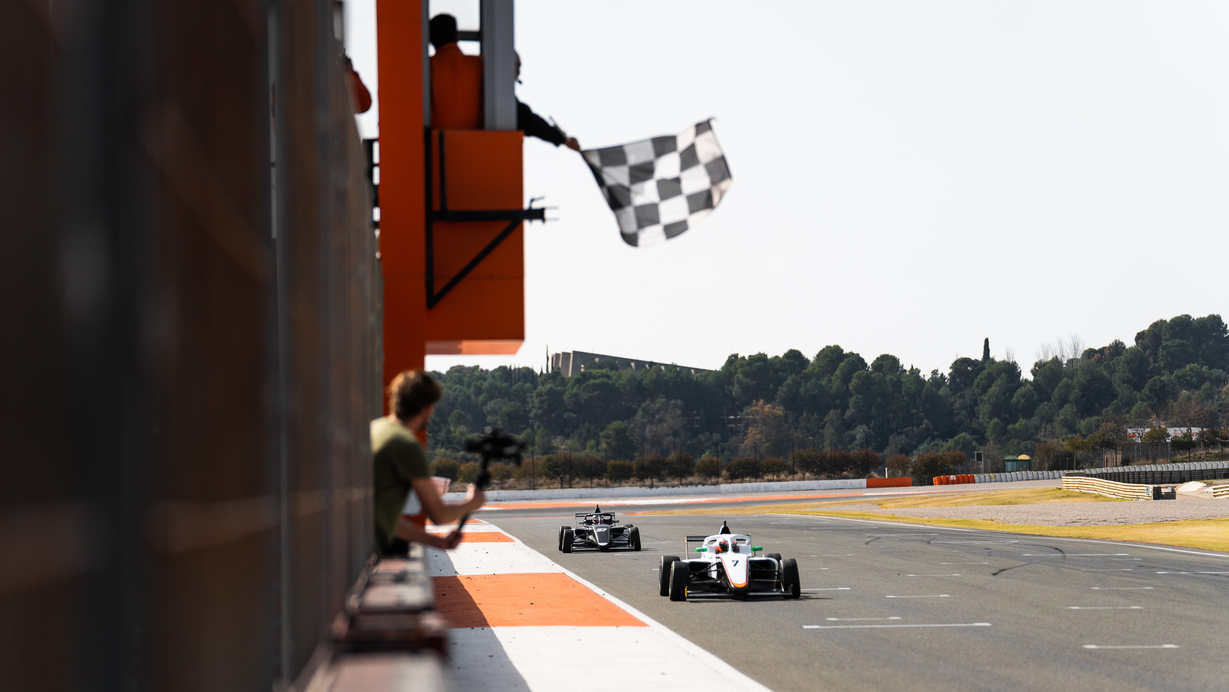 White car crossing the line while the chequered flag is waved