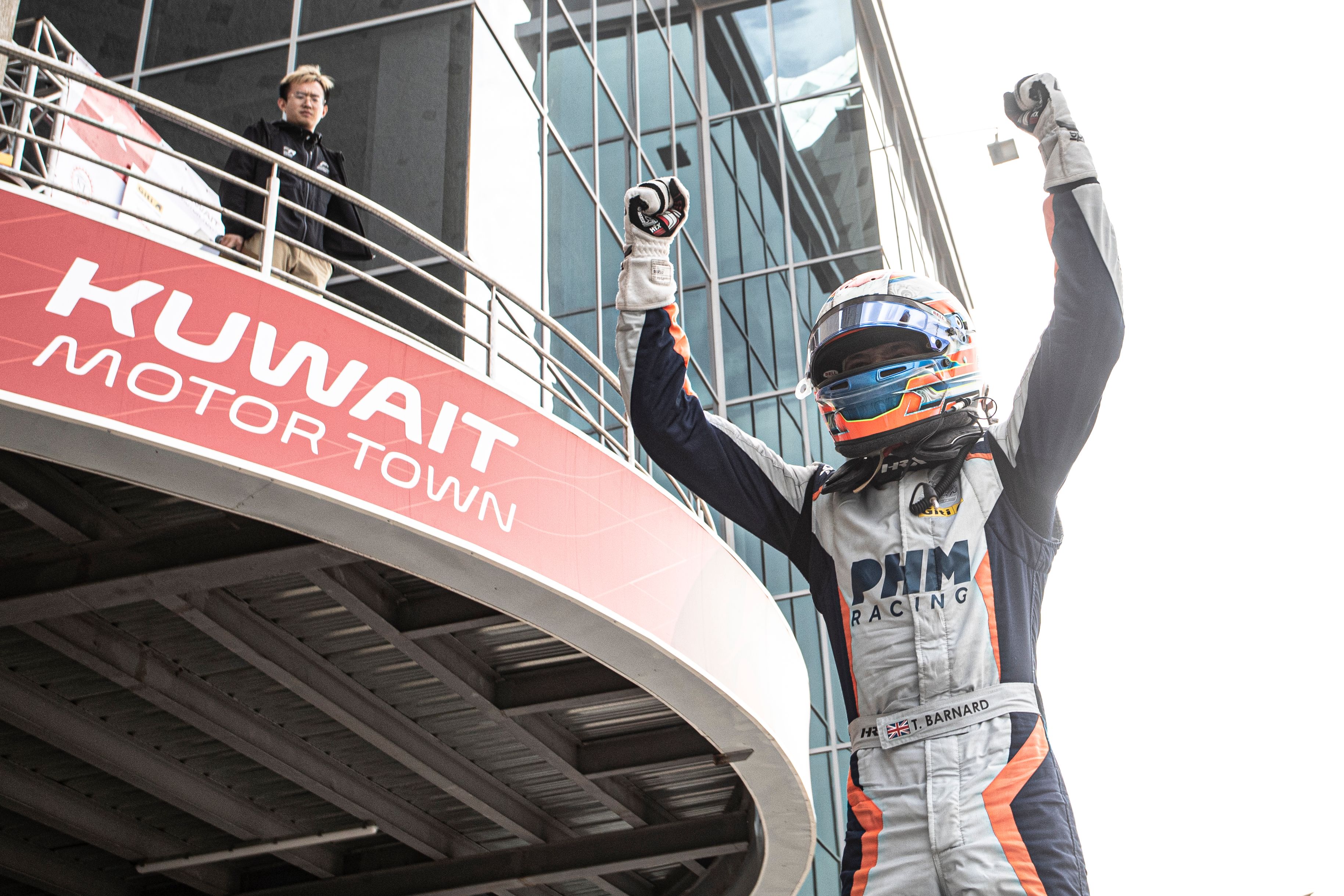 Taylor Barnard wearing his helmet with his arms in the air celebrating his race win