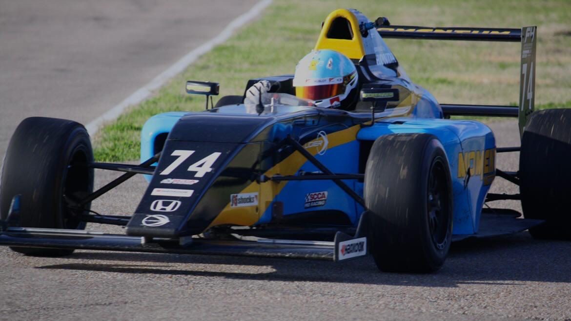 The blue, yellow and black Momentum Motorsports #74 car of Garrett Dettman in focus on track