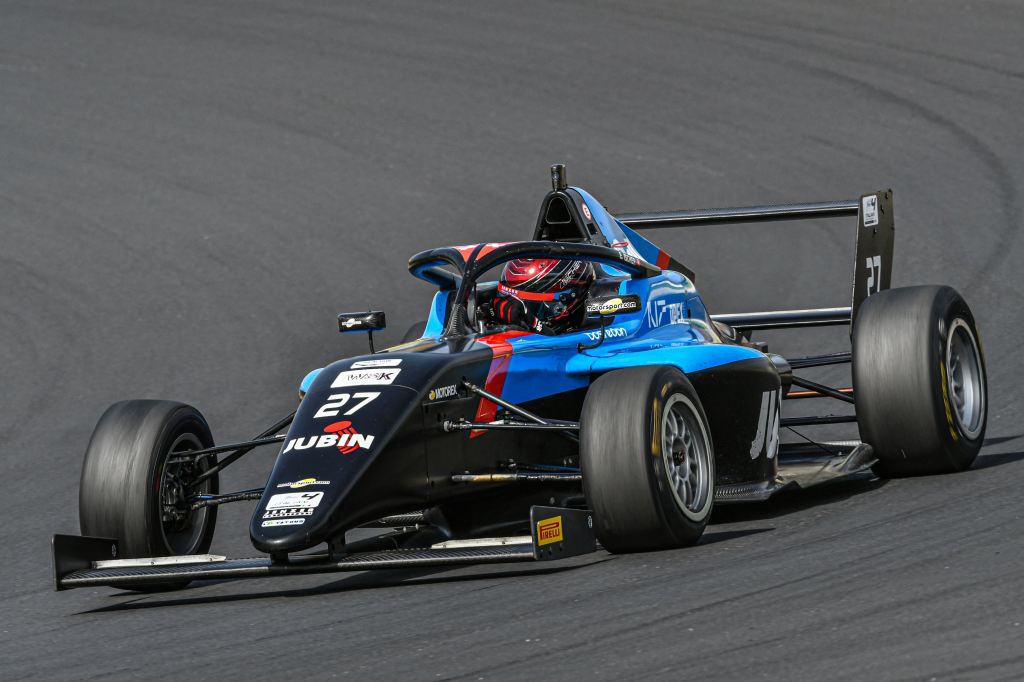 A blue and black Italian F4 car on track