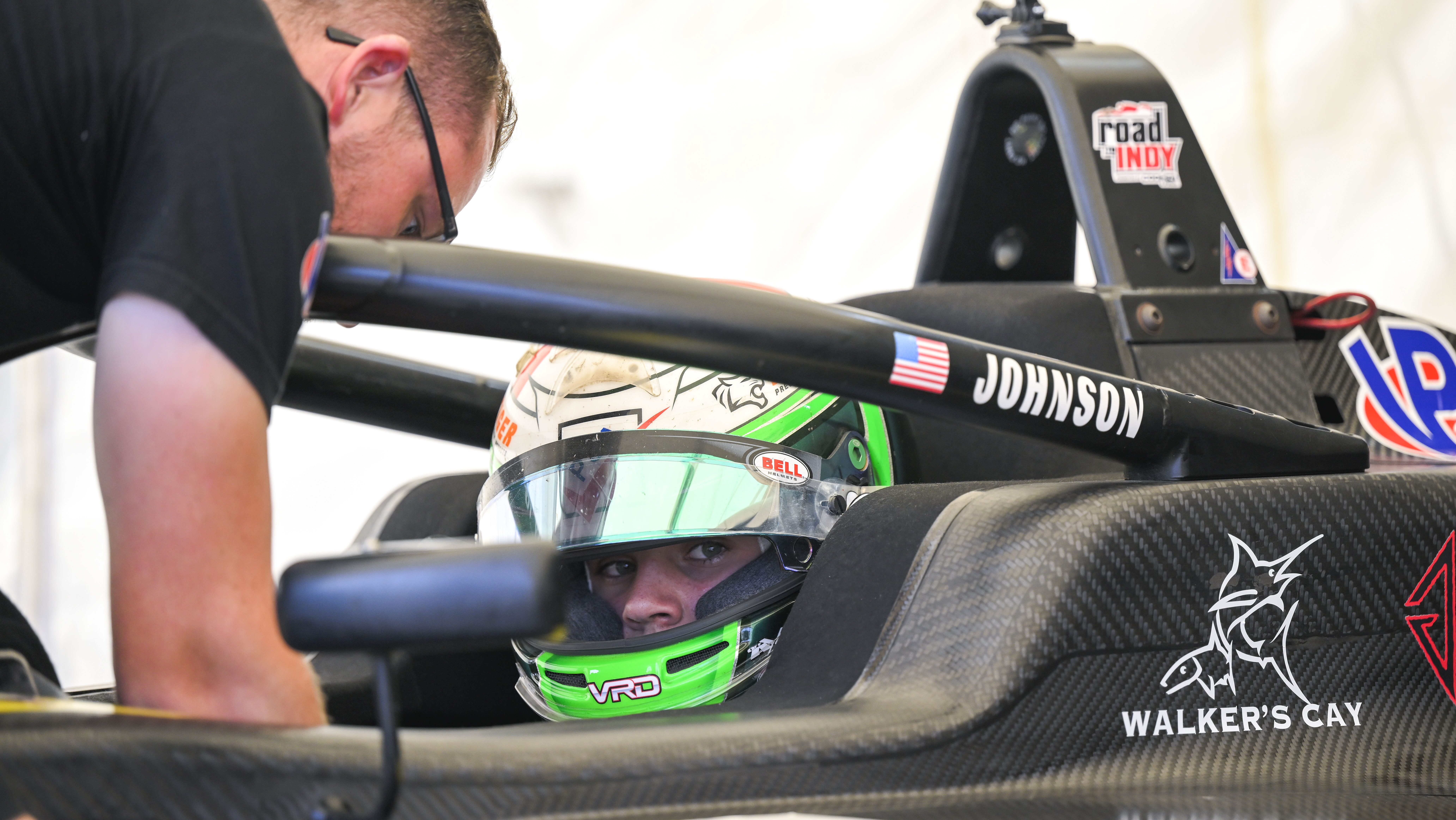 Driver wearing green helmet sat in a black car