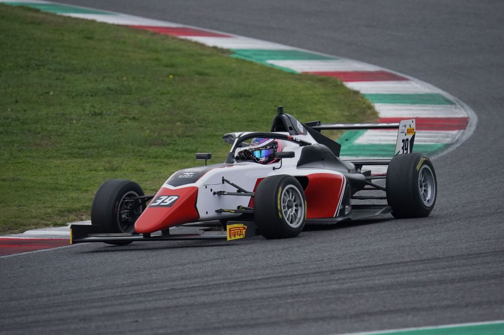 A red and white Italian F4 car on track