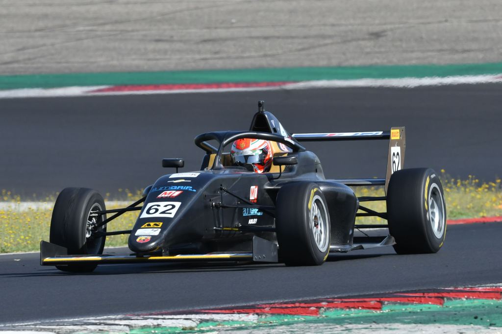 A black Italian F4 car on track