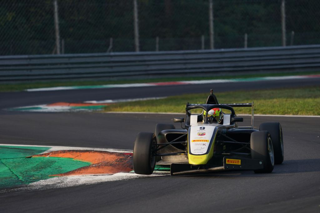 A blue and white Italian F4 car on track