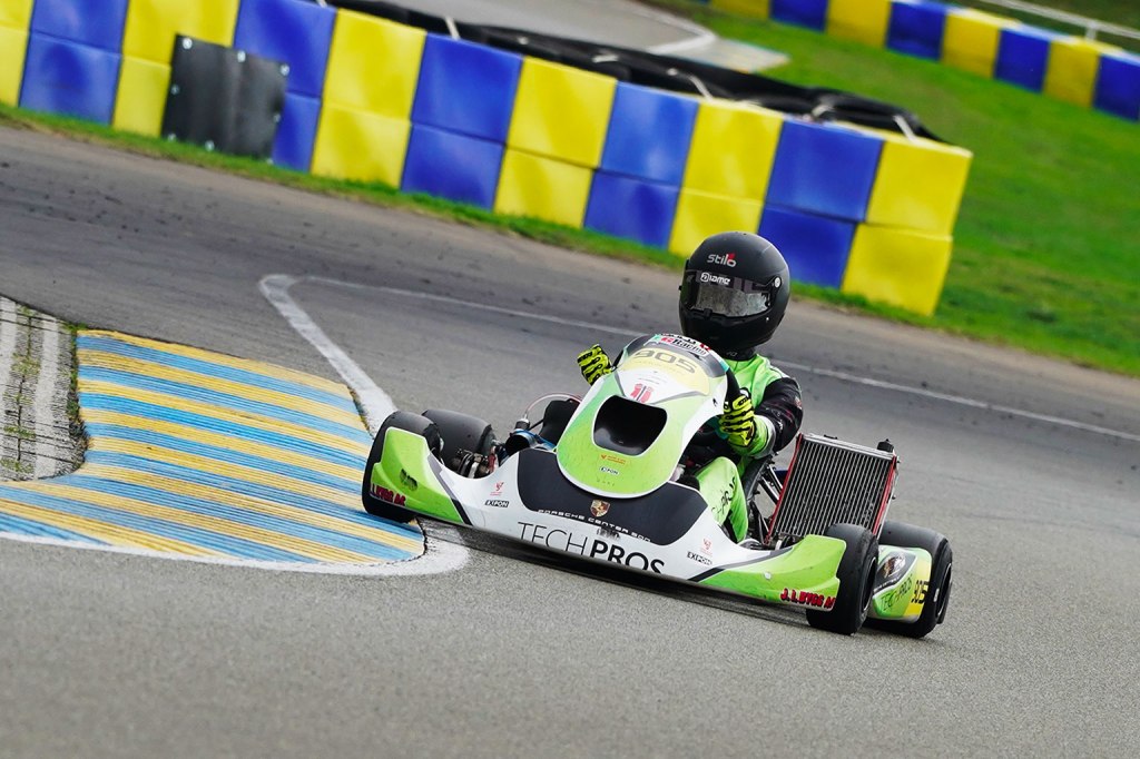 A green shifter kart turning right driven by a racer with a black helmet