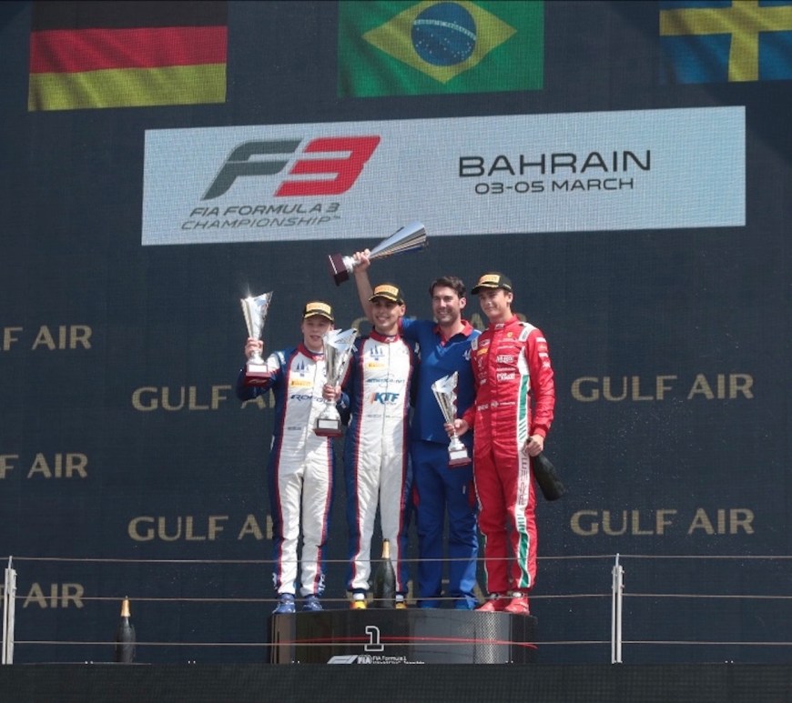 Four men on the #1 step of the podium with the German, Brazilian, and Swedish flags in the background and the text "FIA Formula 3 Championship Bahrain 03–05 March" displayed in the background above Gulf Air sponsorship.