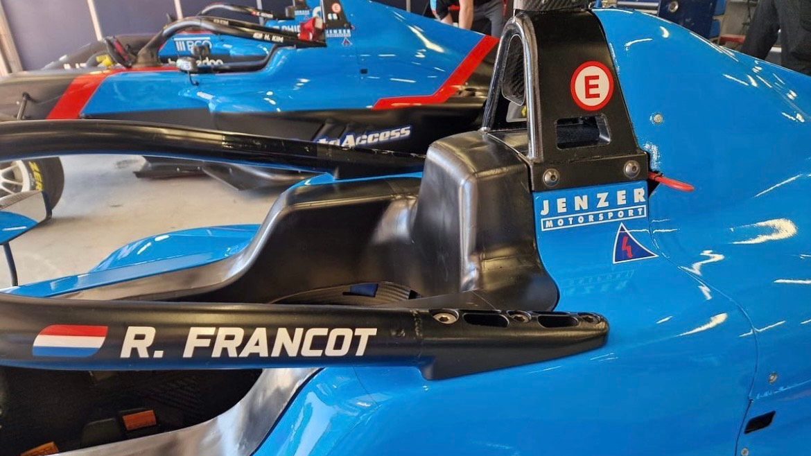 A blue Jenzer Motorsport F4 car photographed from beside the halo
