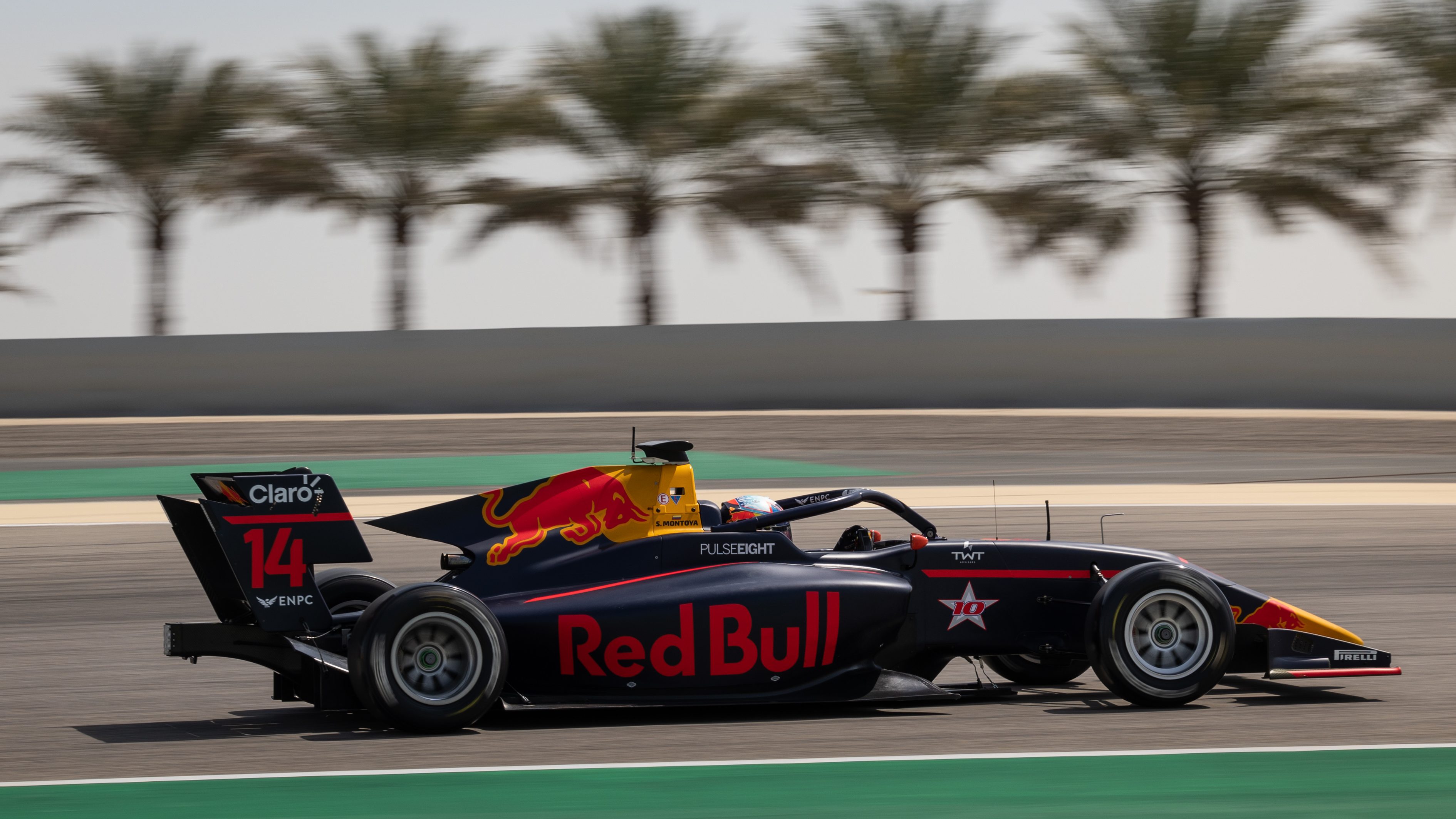 A blue, red and yellow race car driving past palm trees