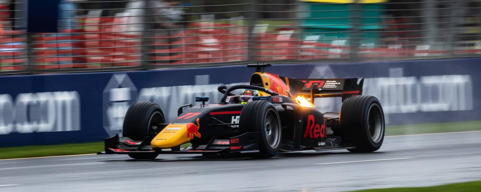 A Red Bull–liveried car in wet conditions facing to the left