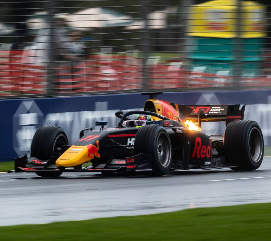 A Red Bull–liveried car in wet conditions facing to the left