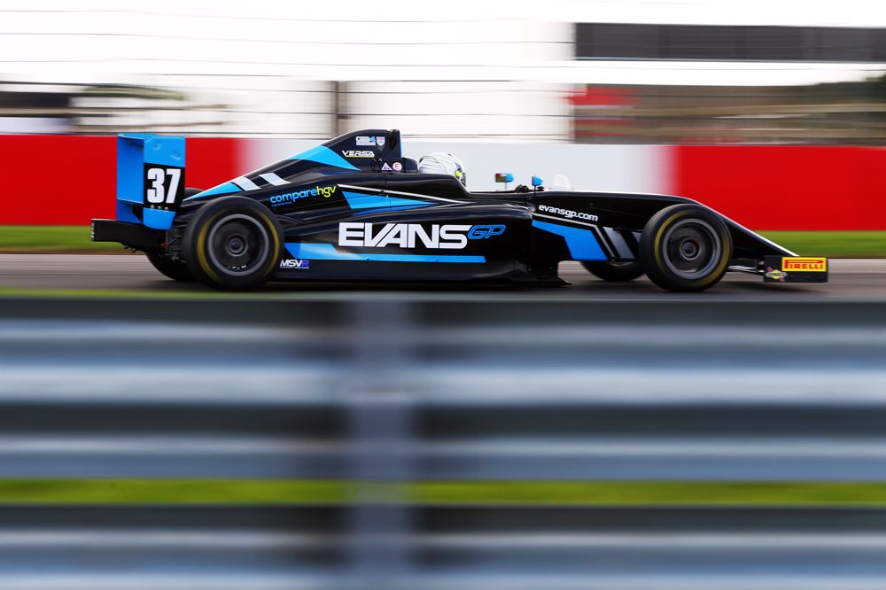 A blue and black car on track photographed from the right