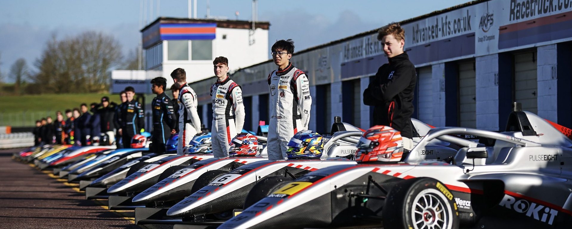 Drivers lined up beside their British F4 cars, with the helmets on the nosecones