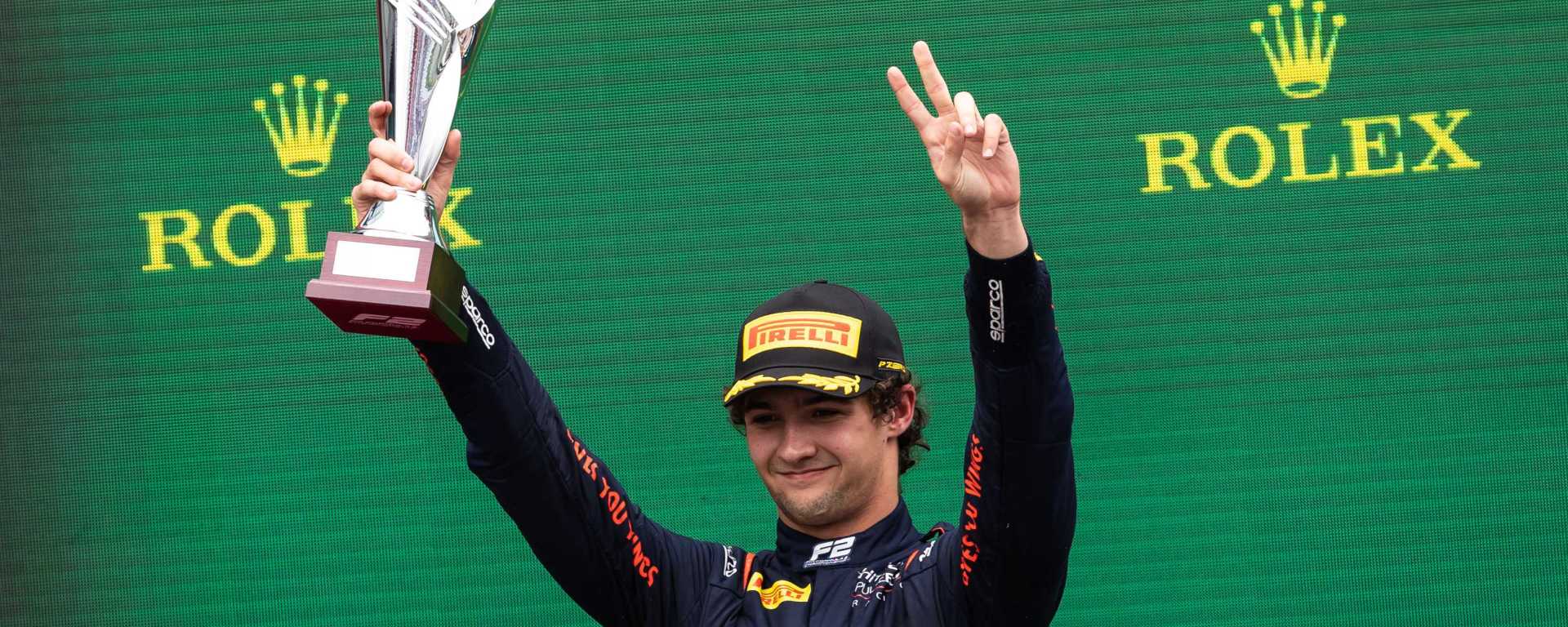 Jak Crawford raises a trophy in his right hand and puts two left-hand fingers in the air