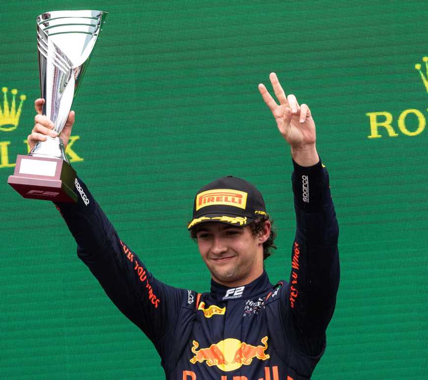 Jak Crawford raises a trophy in his right hand and puts two left-hand fingers in the air