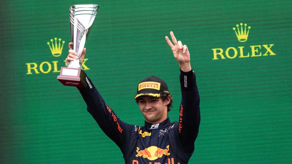 Jak Crawford raises a trophy in his right hand and puts two left-hand fingers in the air