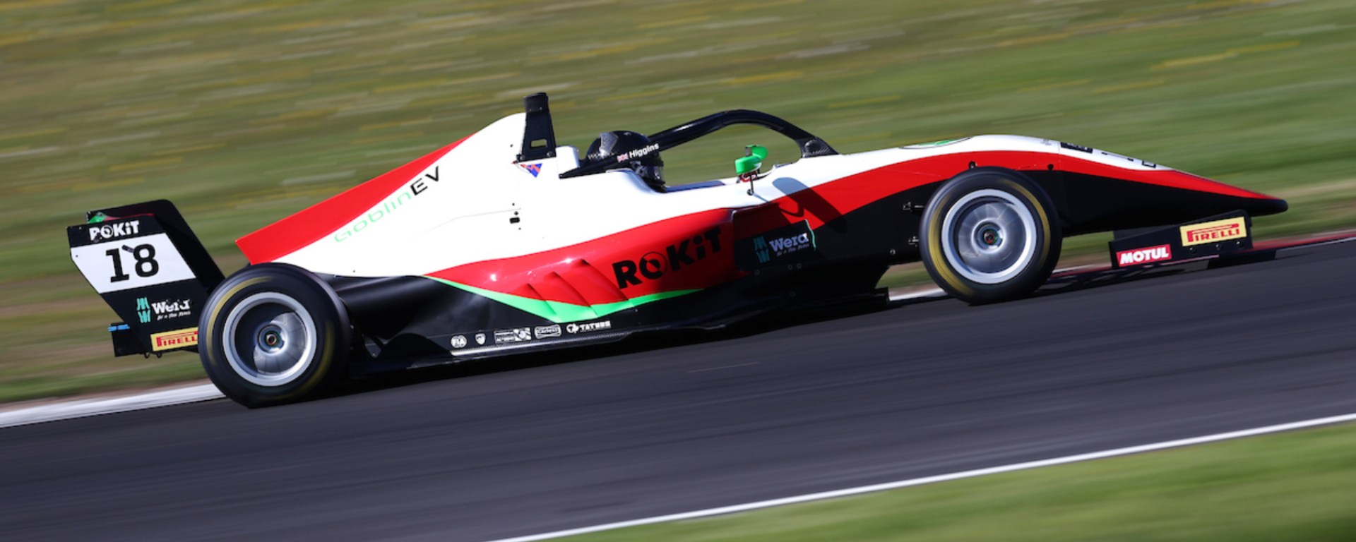 A red and white car on the racetrack photographed from the right