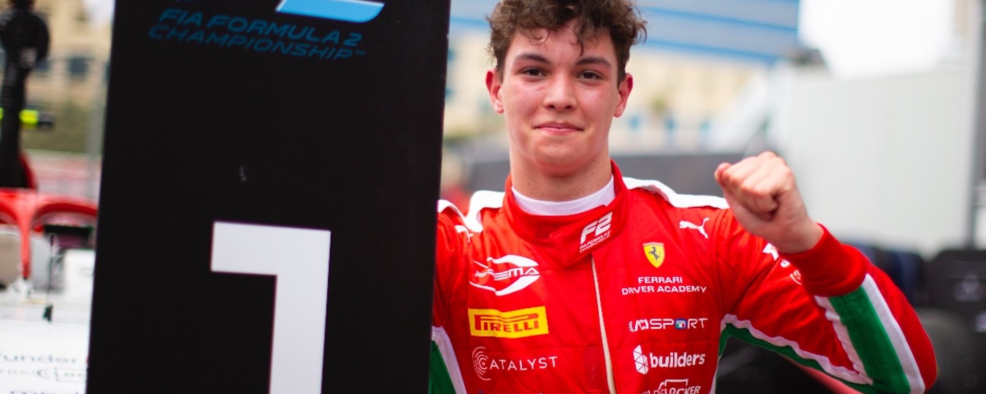 Ollie Bearman holding a P1 sign and pumping his fist, shot from the front