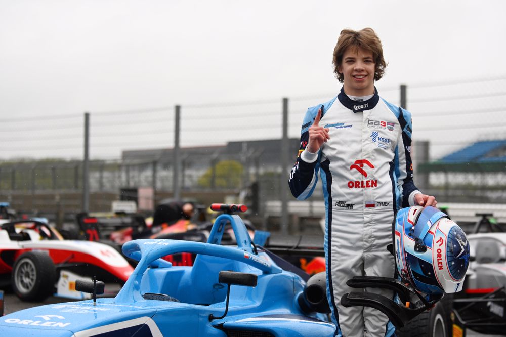 Douglas Motorsport's Tymek Kucharczyk stands next to his GB3 car in the scrutineering bay at Silverstone.