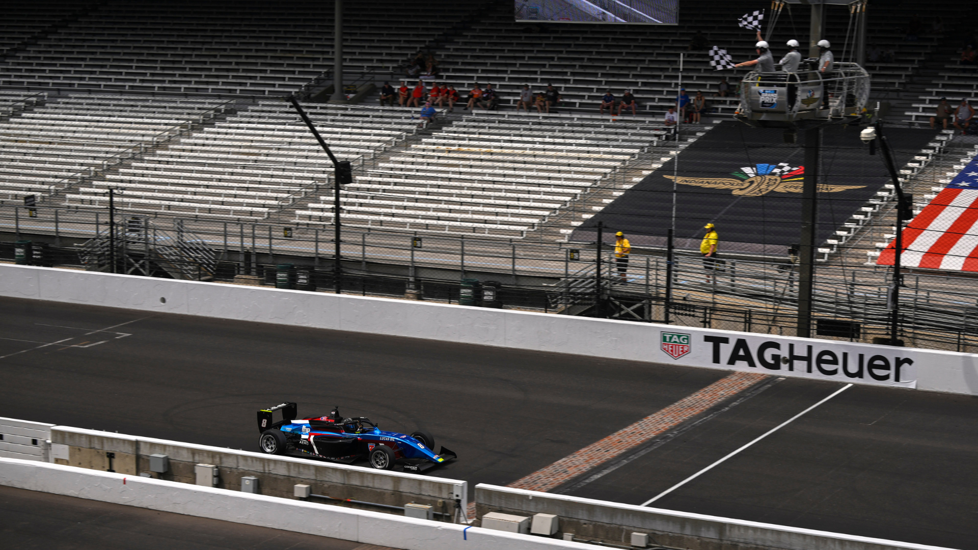 A blue, black and red car takes the chequered flag