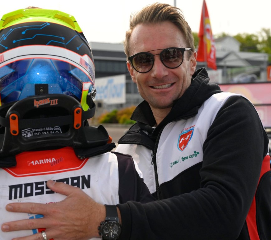 Jay Howard smiling at the camera while placing his hand on the back of Frankie Mossman, who is turned away from the camera