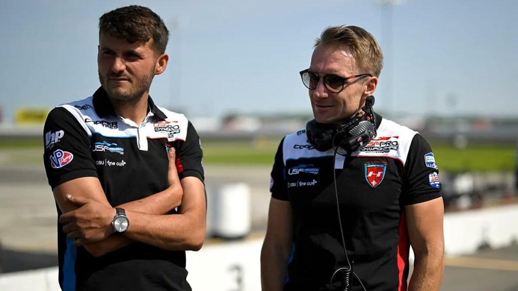 Two men in JHDD outfits standing and looking towards the left