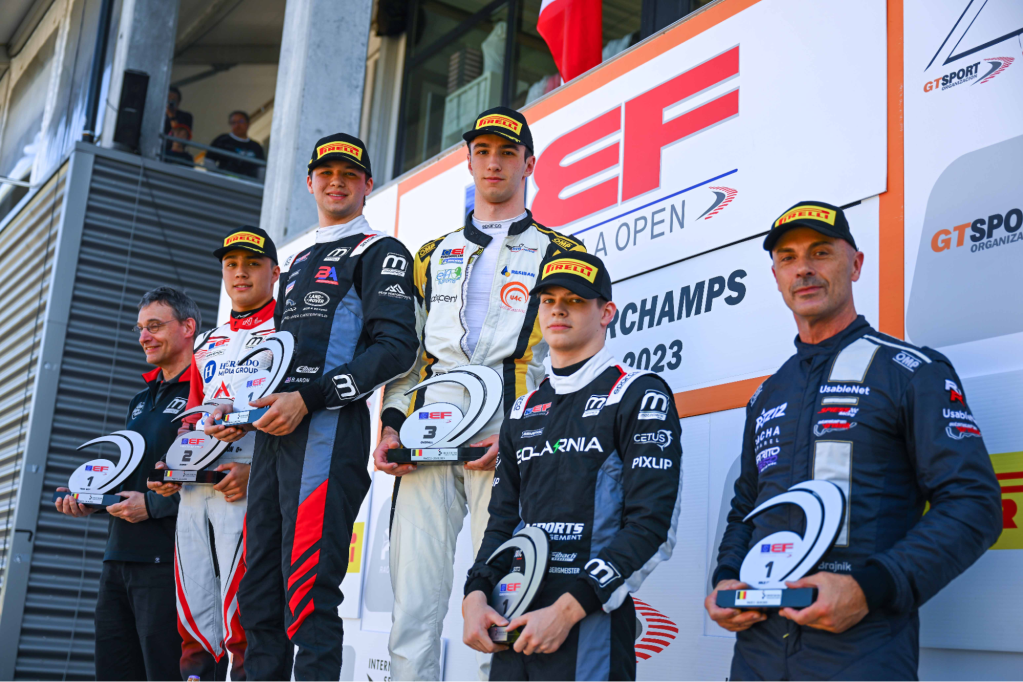 Five drivers holding trophies stand on top of the Euroformula Open podium, with a team representative to their left carrying an additional trophy.