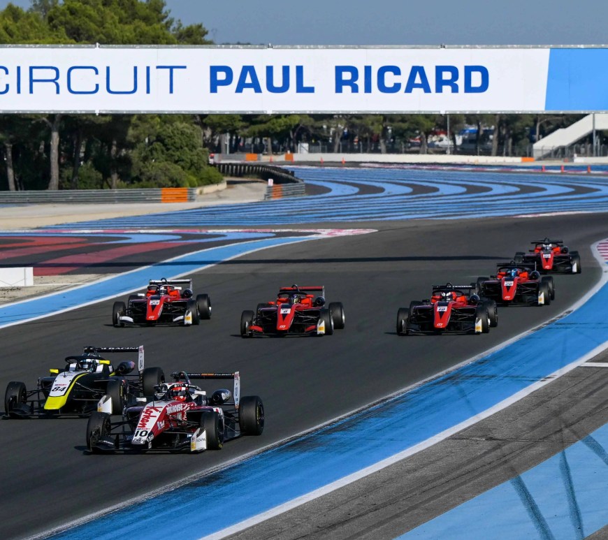 Seven cars on a racetrack with blue run-off