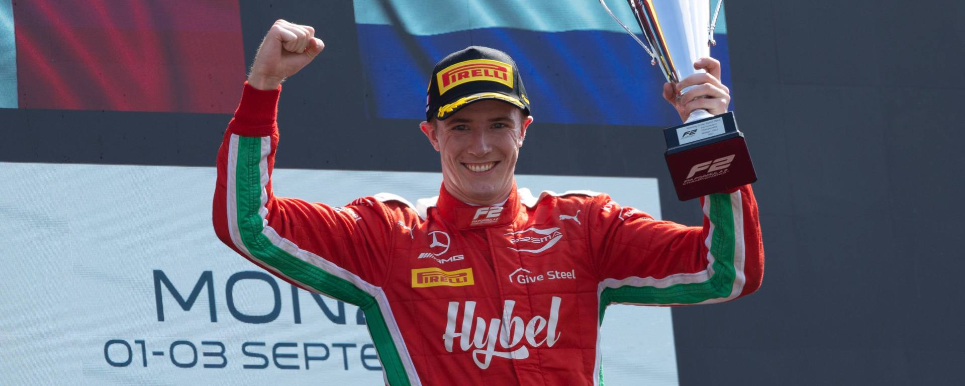 Frederik Vesti lifts a trophy with his left hand on the podium