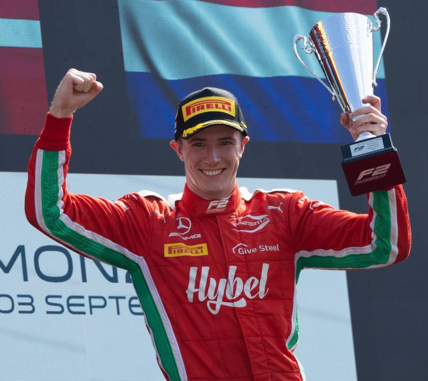 Frederik Vesti lifts a trophy with his left hand on the podium