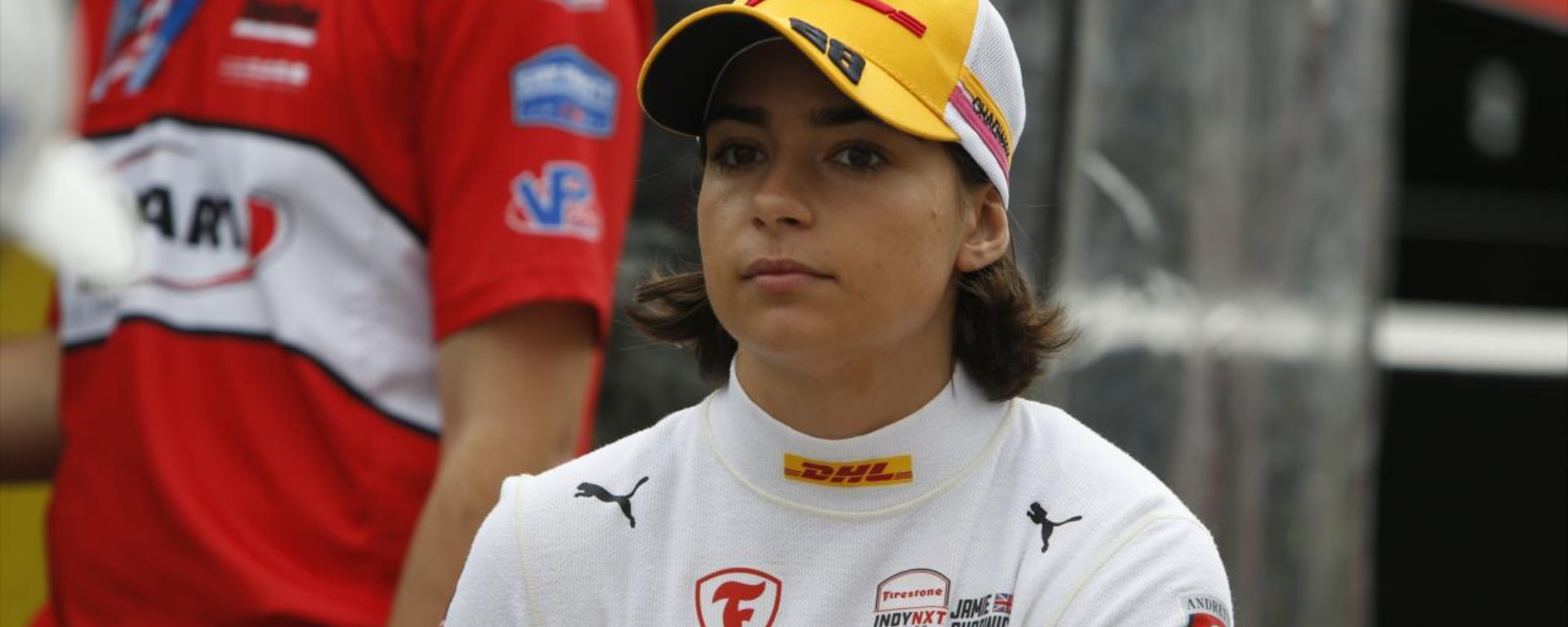 Jamie Chadwick staring at the camera in a yellow DHL cap