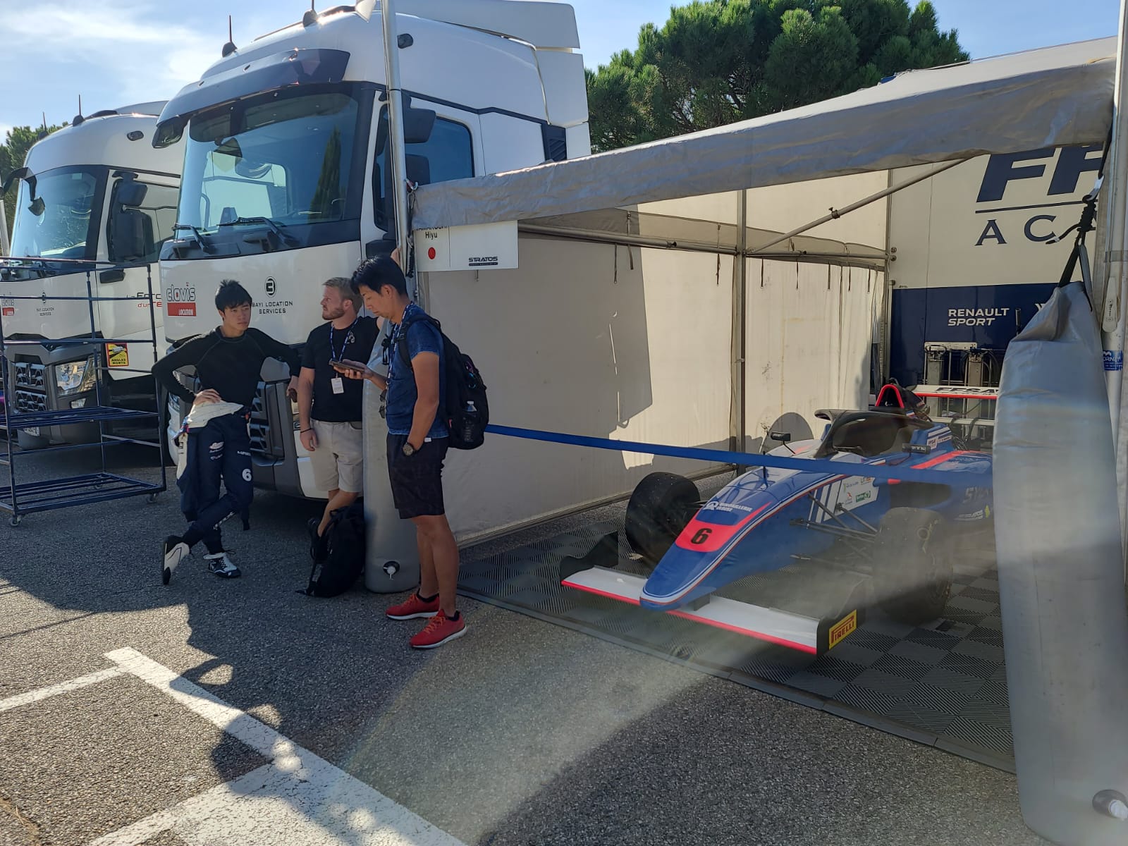 Three people standing beside a roped-off racecar