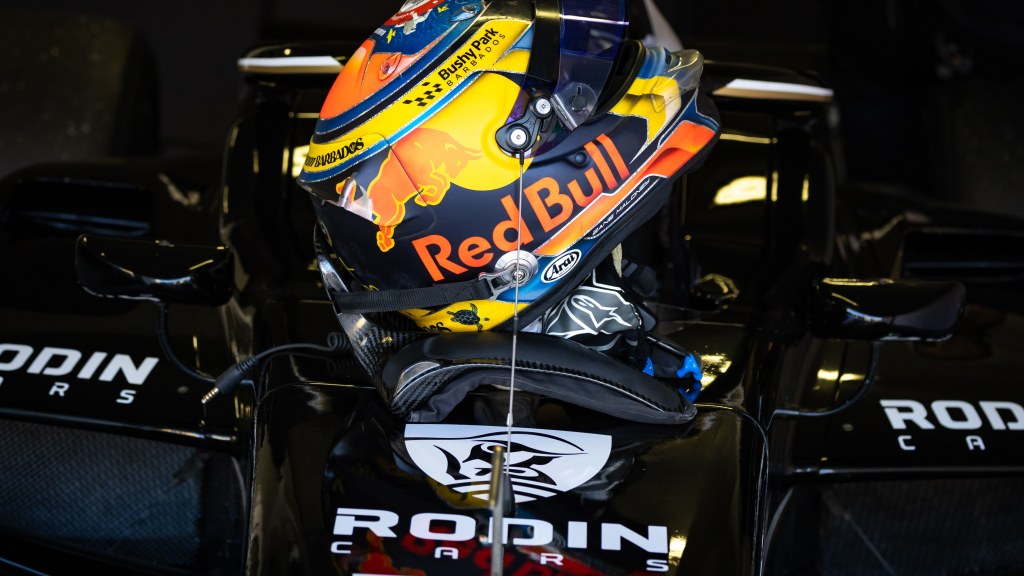 A Red Bull helmet resting on a Rodin Cars–sponsored car