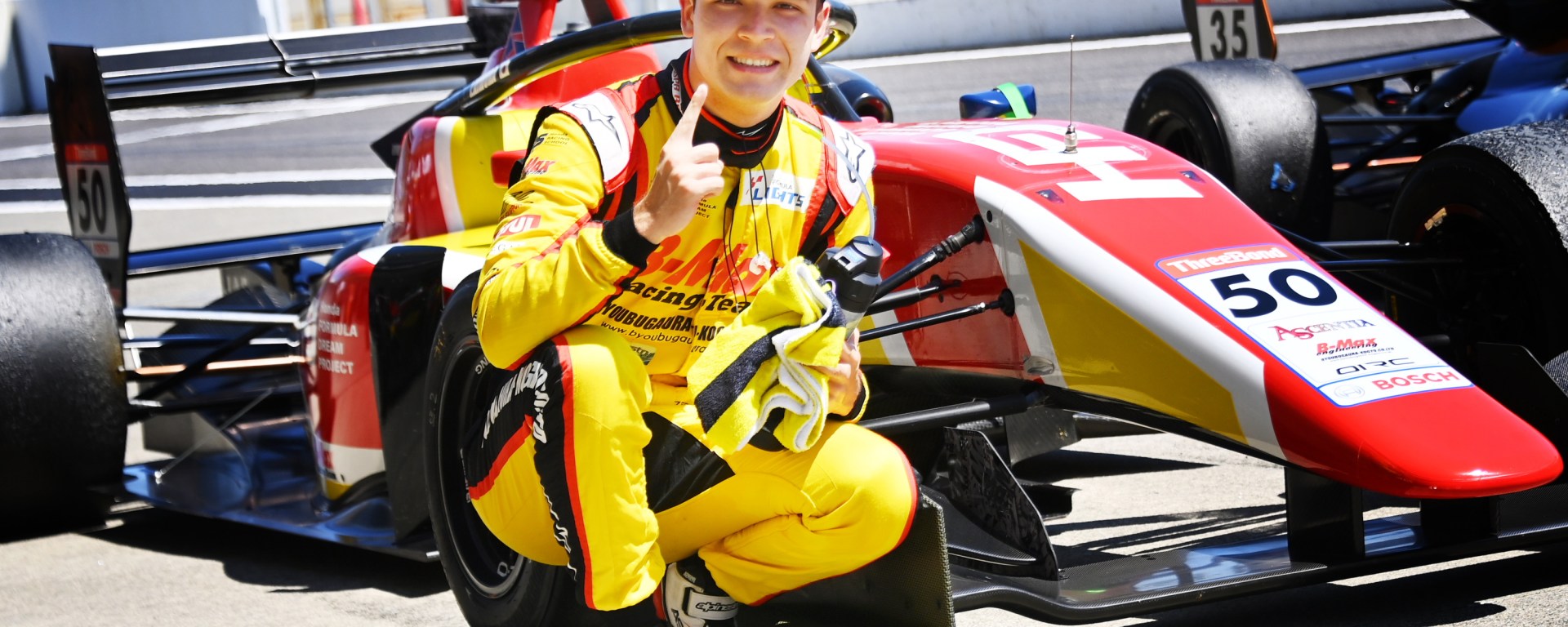 Kimura in front of his car pointing his finger in the air